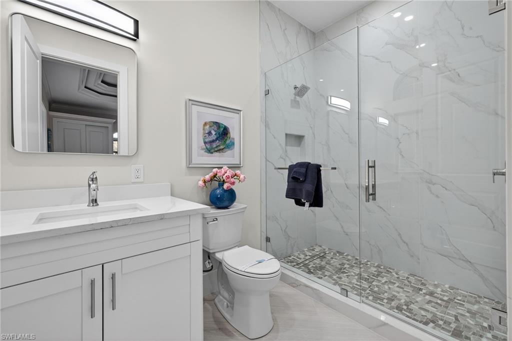 Bathroom featuring vanity and a marble finish shower