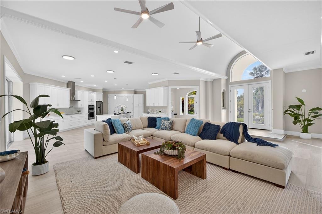 Living area featuring french doors, lofted ceiling, ornamental molding, ceiling fan, and light wood finished floors