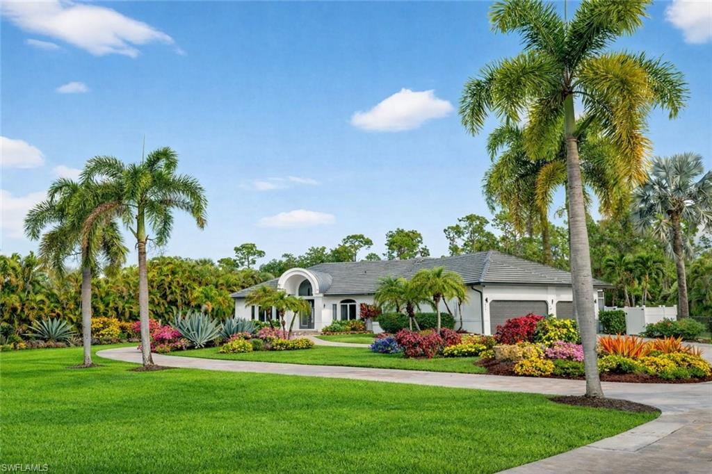 Ranch-style house with a front lawn, an attached garage, driveway, and stucco siding