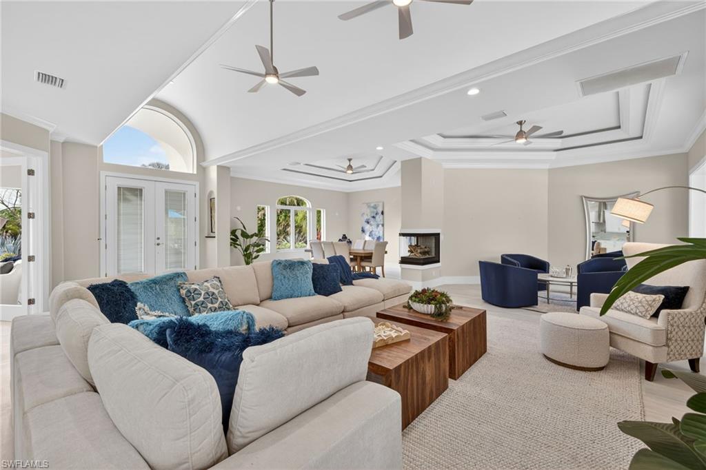 Living room with crown molding, french doors, wood finished floors, a raised ceiling, and a ceiling fan