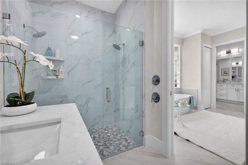 Bathroom with vanity, a marble finish shower, ornamental molding, light wood-type flooring, and a soaking tub
