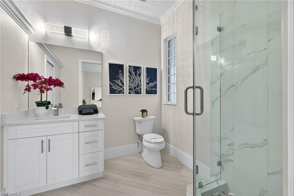 Bathroom featuring vanity, a marble finish shower, and crown molding