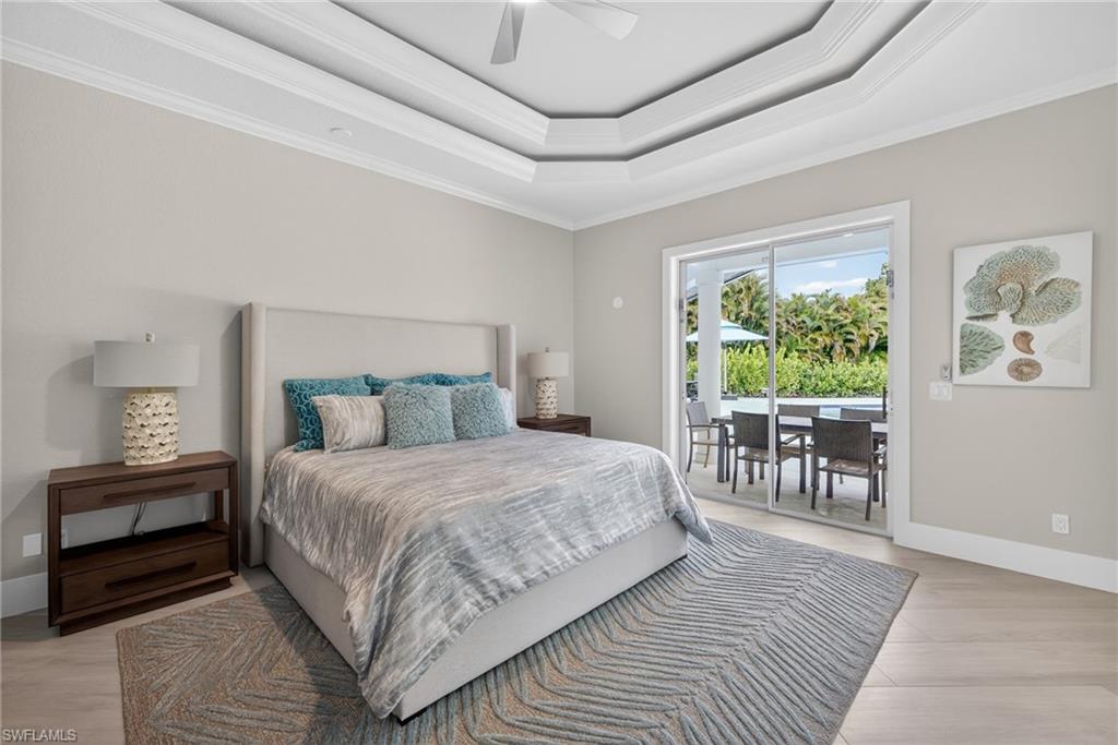 Bedroom featuring crown molding, access to outside, a ceiling fan, a raised ceiling, and light wood-style floors