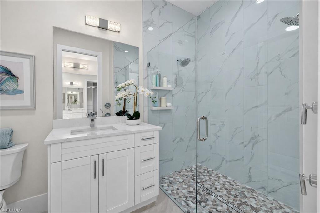 Bathroom featuring a marble finish shower and vanity