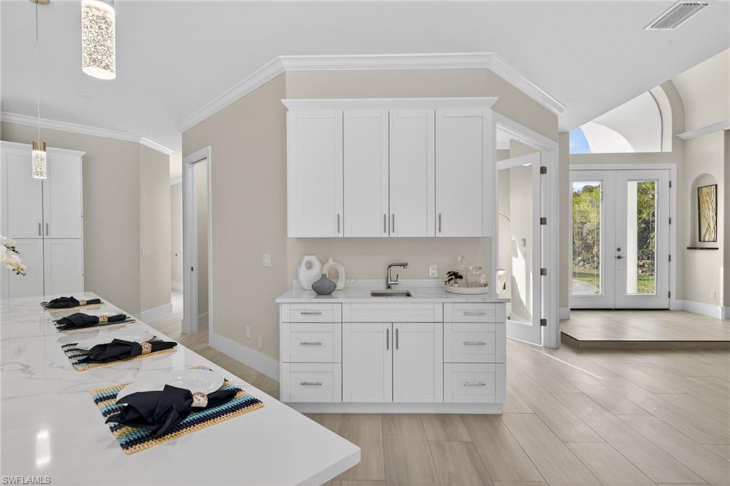 Kitchen with french doors, white cabinets, light stone countertops, decorative light fixtures, and light wood finished floors