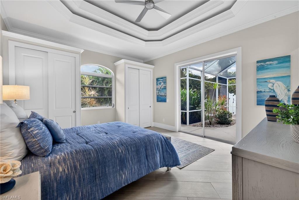 Bedroom featuring a sunroom, two closets, access to exterior, crown molding, and a raised ceiling
