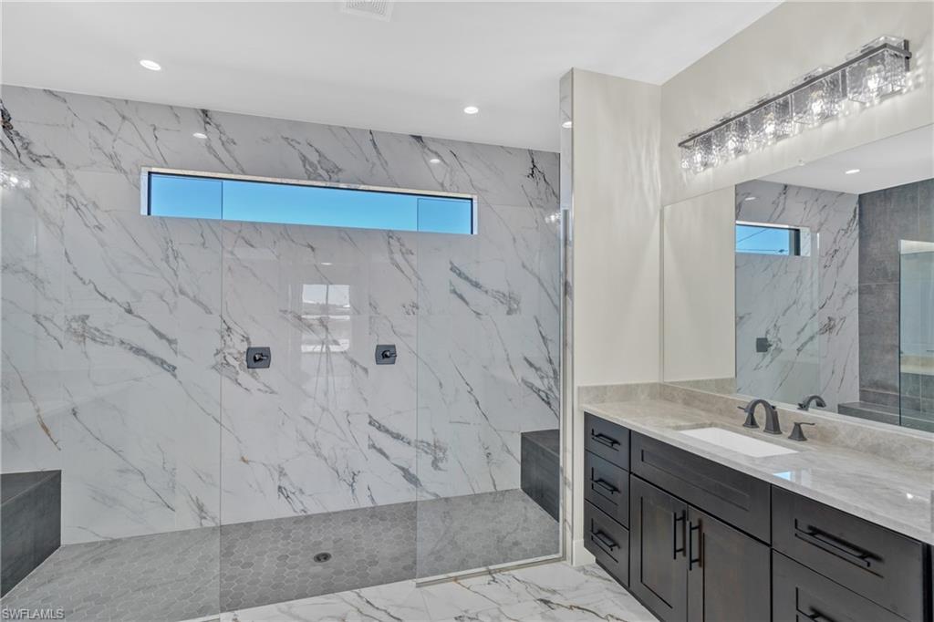 Bathroom with vanity, a marble finish shower, plenty of natural light, and recessed lighting
