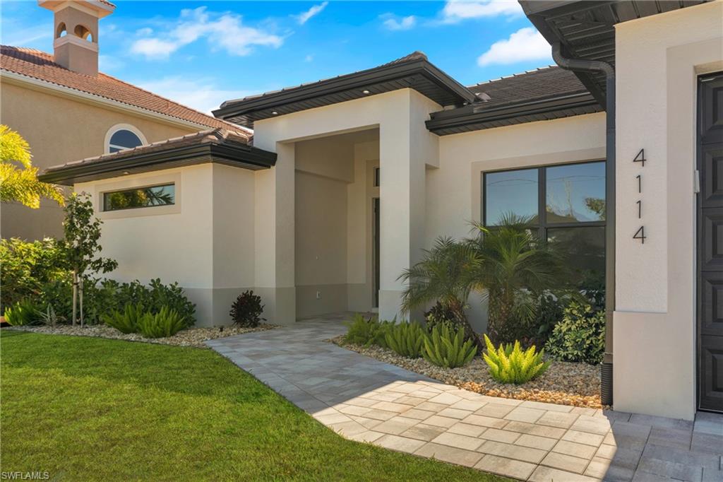Entrance to property with a yard, stucco siding, and a tile roof