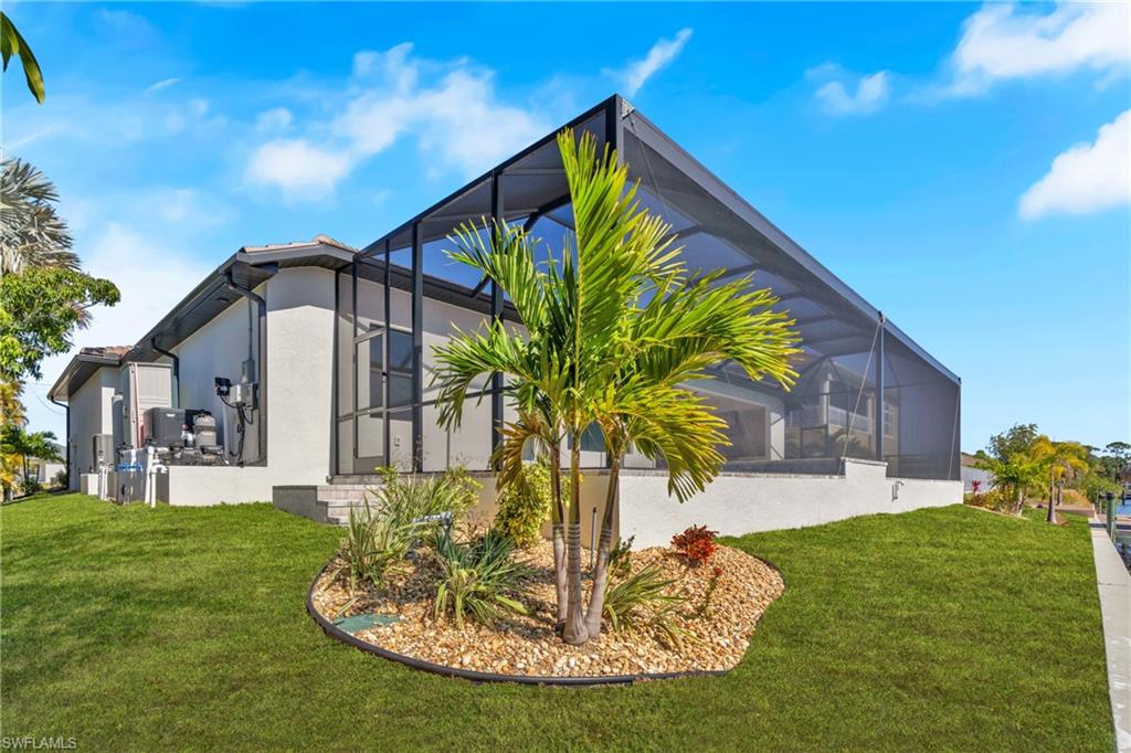 View of side of property with a sunroom, a lanai, a lawn, and stucco siding