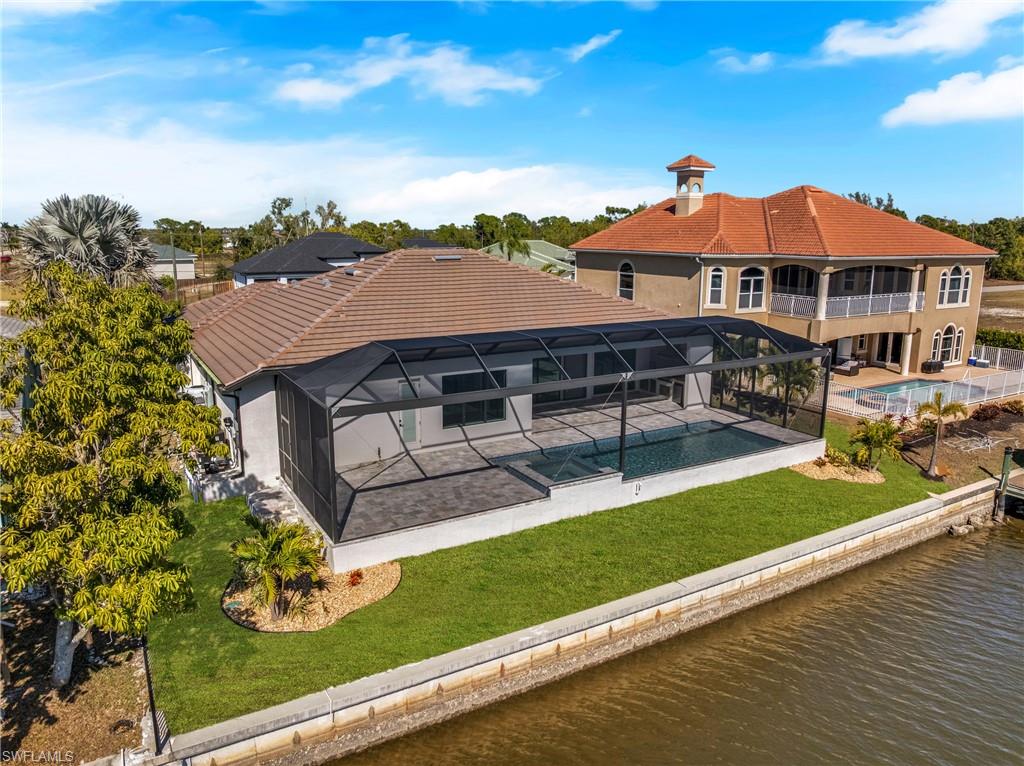 Rear view of property with an outdoor pool, a yard, a tiled roof, a water view, and glass enclosure
