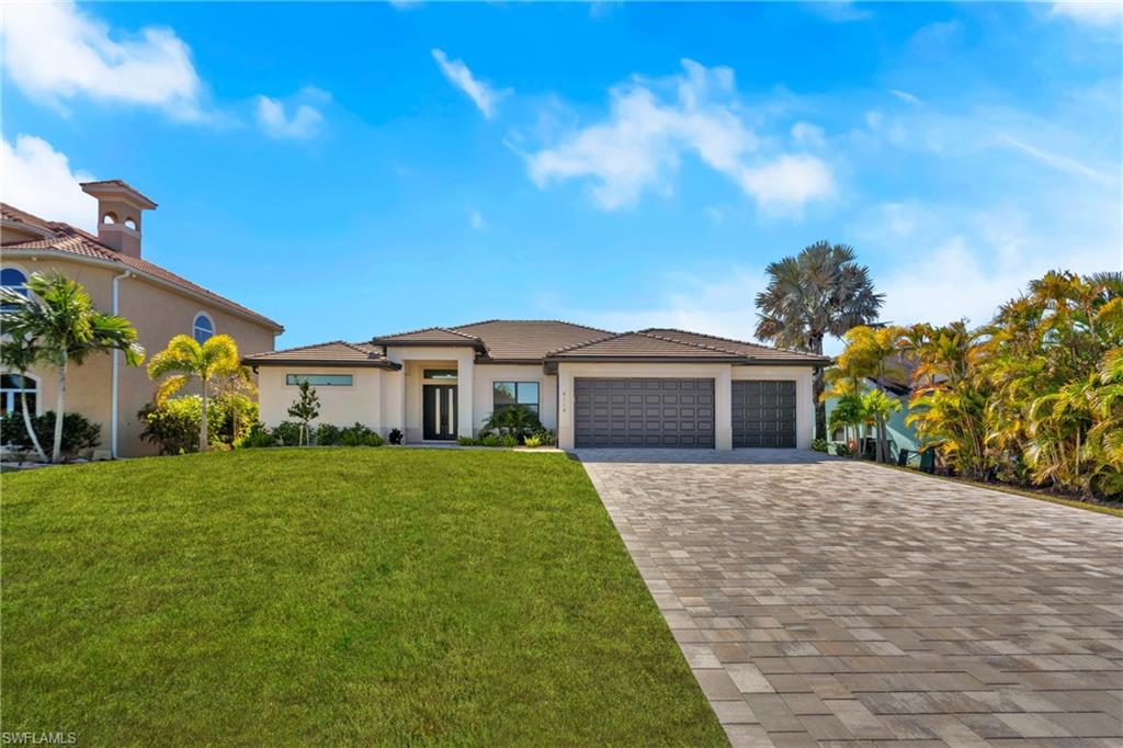 Prairie-style house featuring a front yard, stucco siding, decorative driveway, and an attached garage