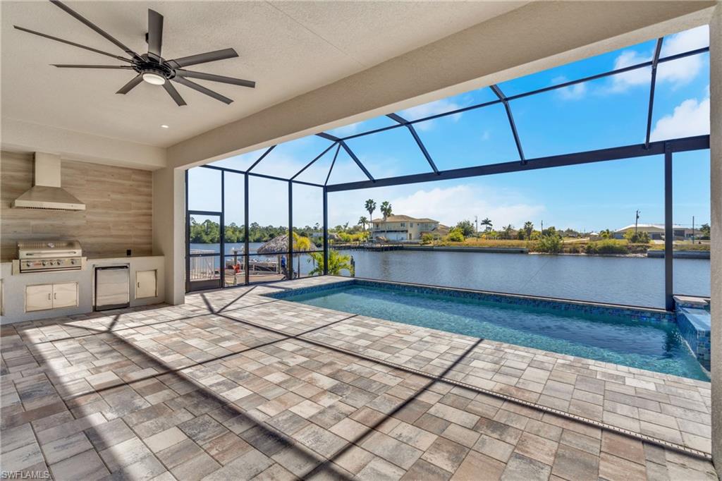 Outdoor pool featuring area for grilling, a sunroom, a patio, a lanai, and a water view