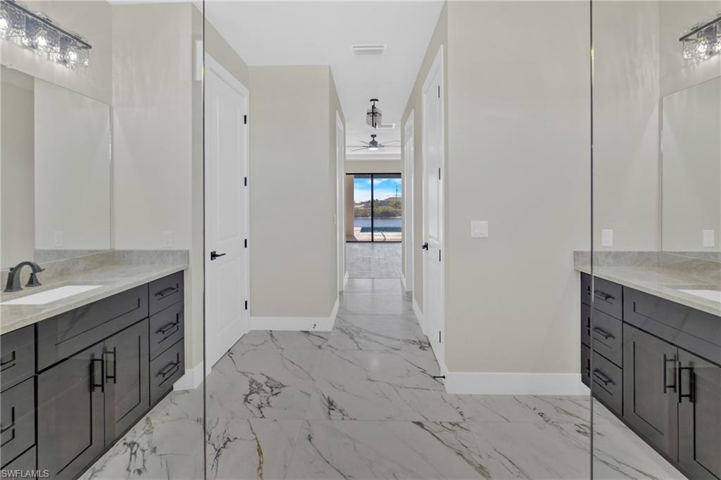 Bathroom featuring vanity, light marble finish flooring, and ceiling fan