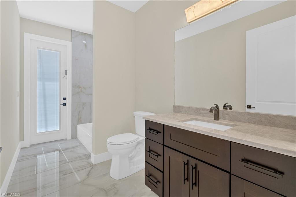 Full bathroom featuring light marble finish floors, vanity, and shower / bath combination