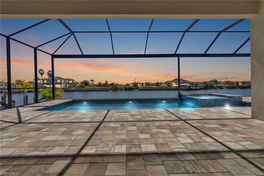 Pool at dusk with a lanai, a pool with connected hot tub, a patio, and a sunroom