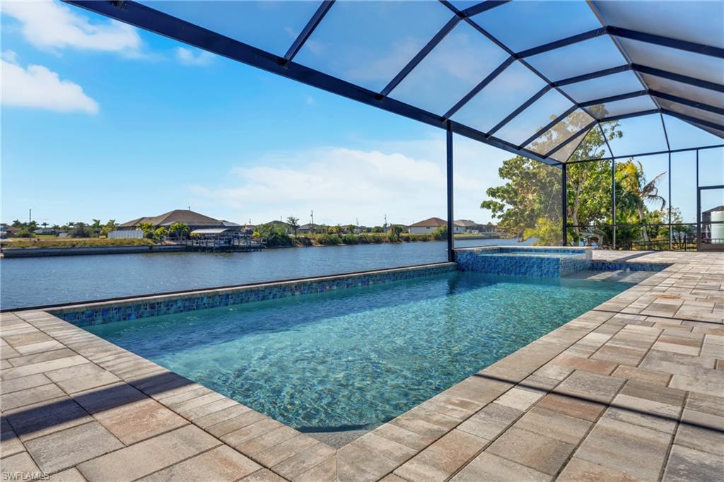 Relaxing pool / spa with a lanai, a patio area, a sunroom, and a water view