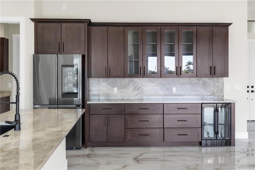 Kitchen with smart refrigerator, wine cooler, glass insert cabinets, and light stone counters