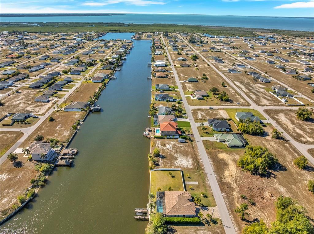 Aerial view of property and surrounding area featuring a nearby body of water and nearby suburban area