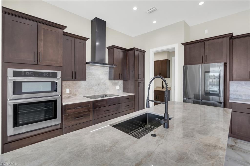 Kitchen featuring decorative backsplash, stainless steel appliances, dark wood finish cabinetry, and recessed lighting