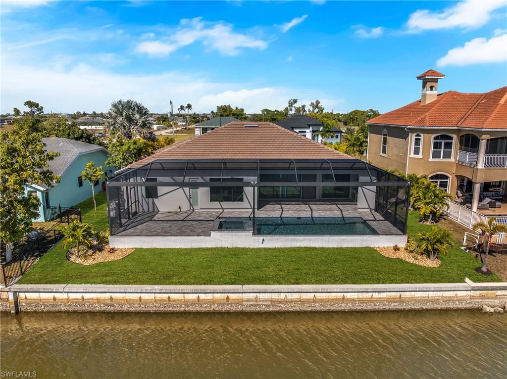 Rear view of property featuring a sunroom, an outdoor pool, glass enclosure, and a water view