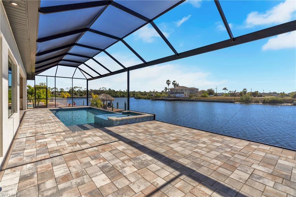 Integrated pool / hot tub featuring a sunroom, a lanai, a patio area, and a water view
