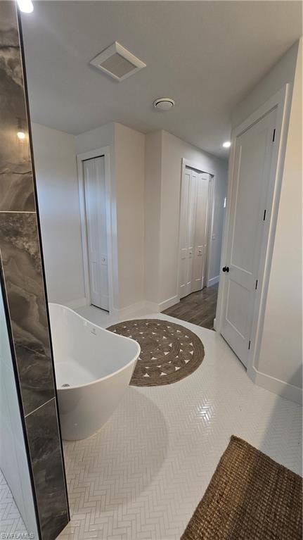 Bathroom featuring a soaking tub, a closet, and recessed lighting