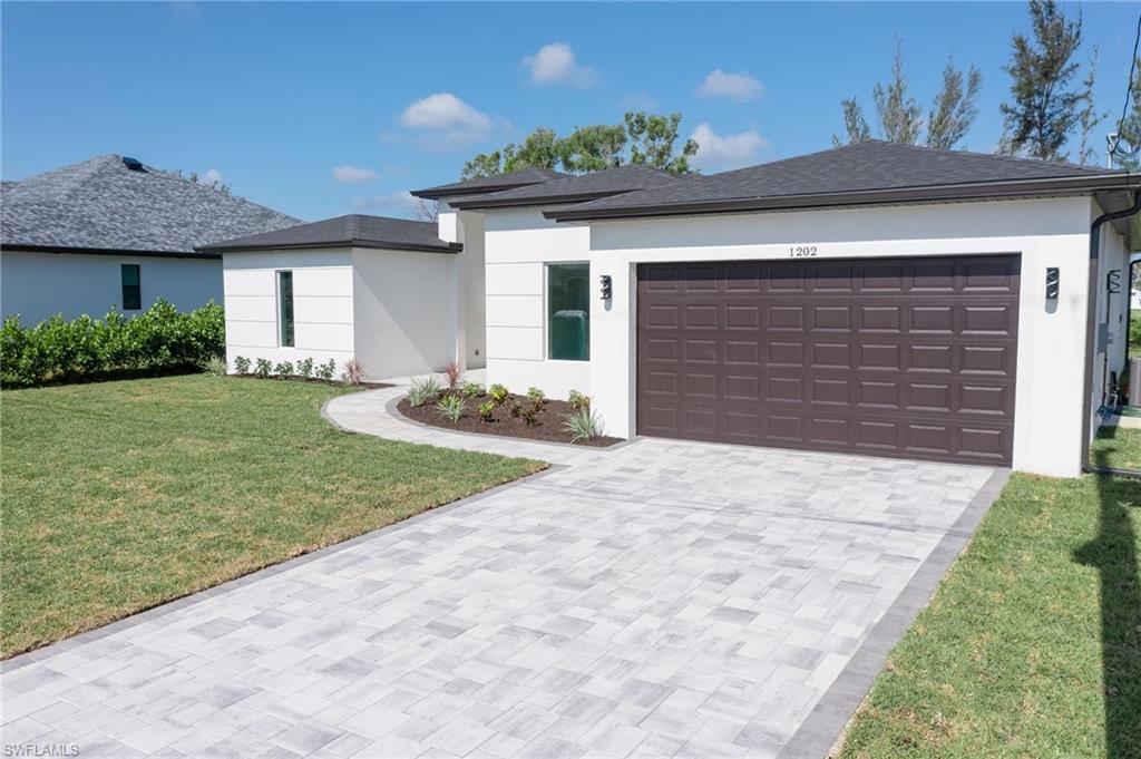 View of front facade with a front lawn, driveway, stucco siding, and an attached garage