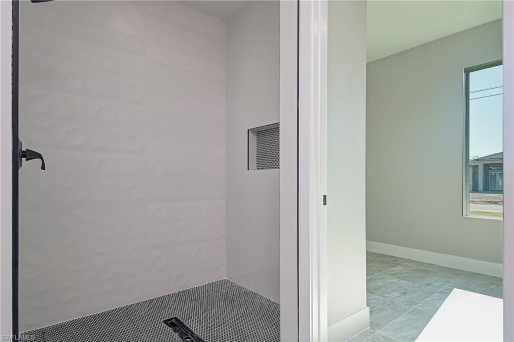 Full bath featuring a tile shower and baseboards
