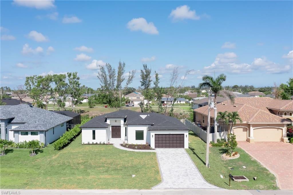 View of front of home with a residential view, decorative driveway, and a garage