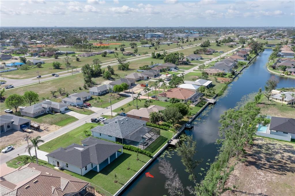 Aerial view of property and surrounding area featuring a large body of water and nearby suburban area