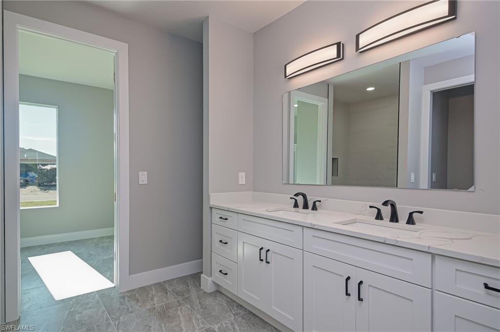 Bathroom with double vanity and baseboards