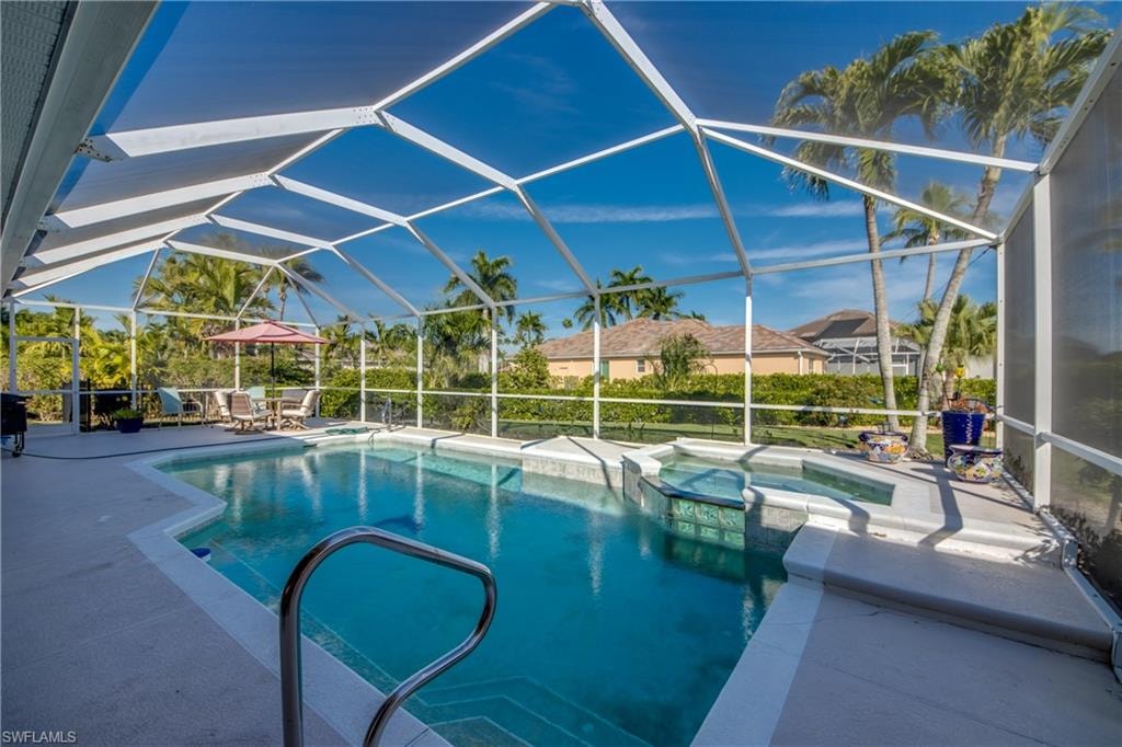 Combined pool / hot tub with a sunroom, a patio area, and glass enclosure