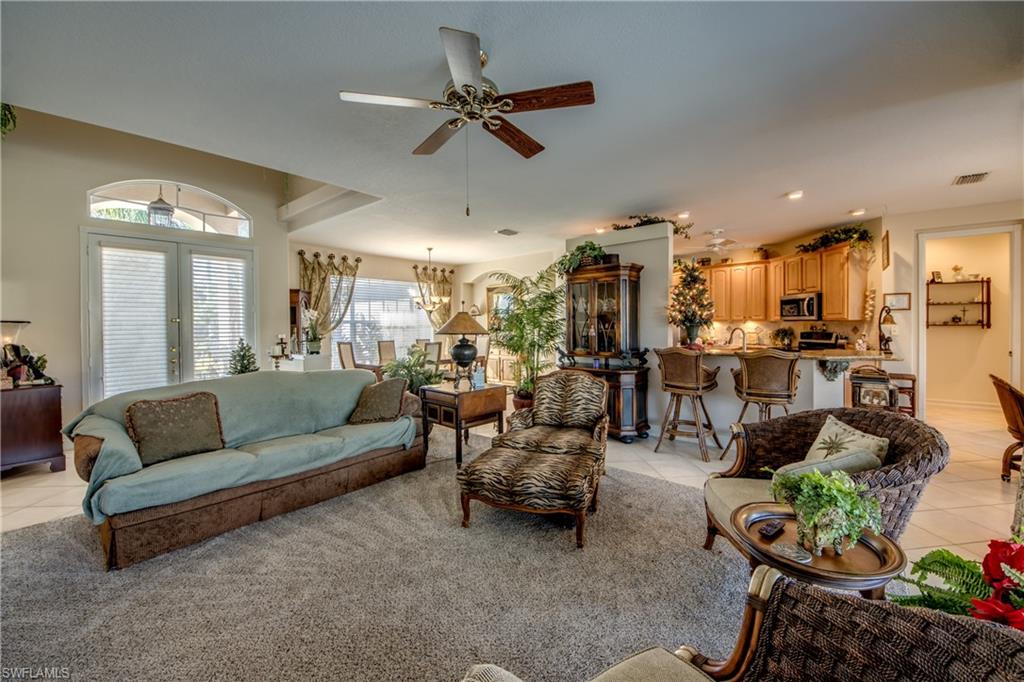 Living area with light tile patterned flooring, a ceiling fan, and suspended lighting
