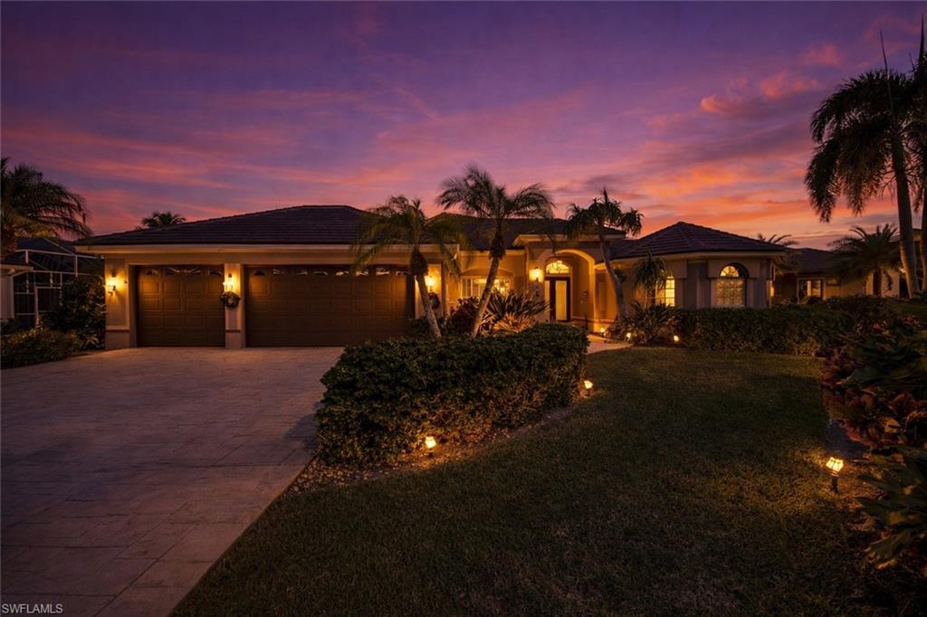 View of front of property with driveway, a garage, a yard, stucco siding, and a tiled roof
