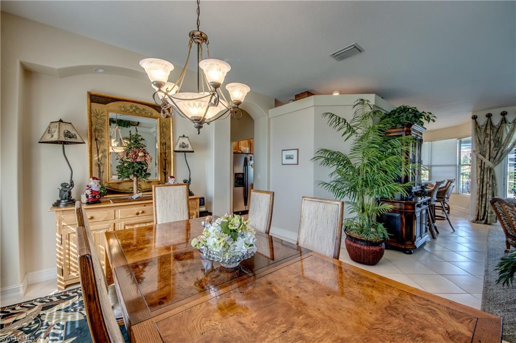 Dining area with light tile patterned floors, suspended lighting, and arched walkways