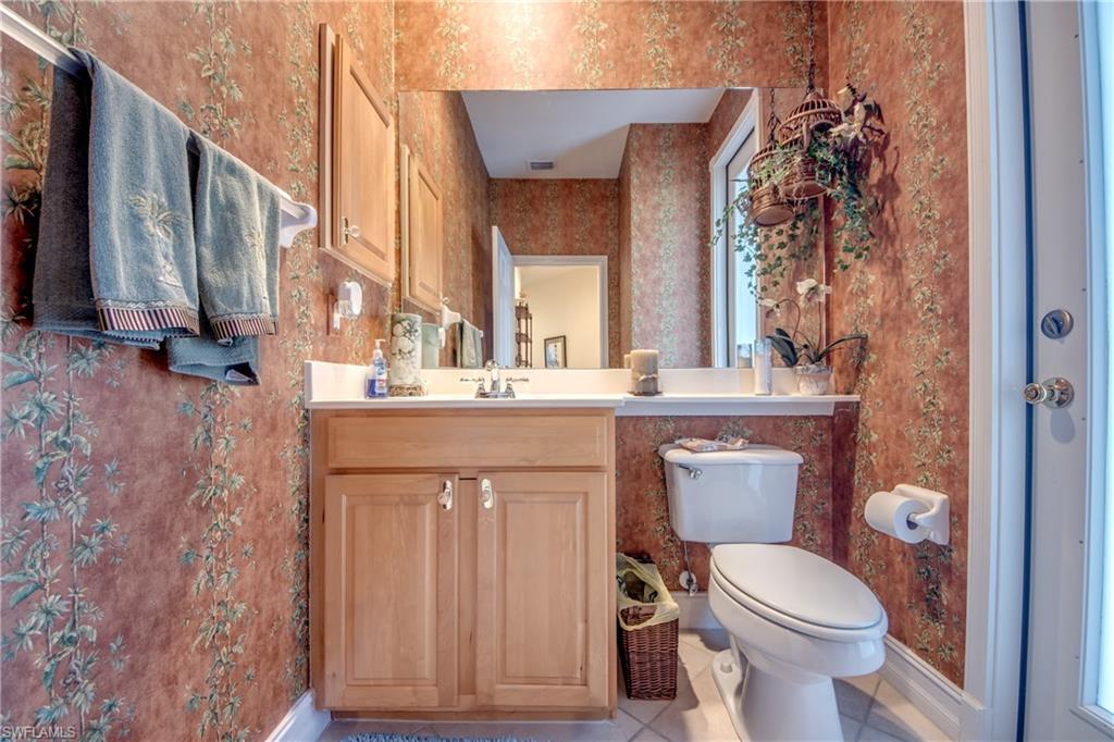 Half bathroom with vanity, light tile patterned floors, and wallpapered walls