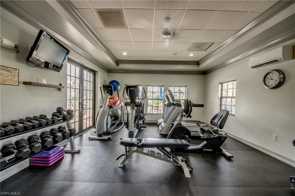 Exercise room with ornamental molding, a drop ceiling, and a raised ceiling