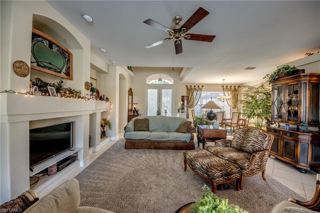 Living room featuring light tile patterned floors, arched walkways, and ceiling fan