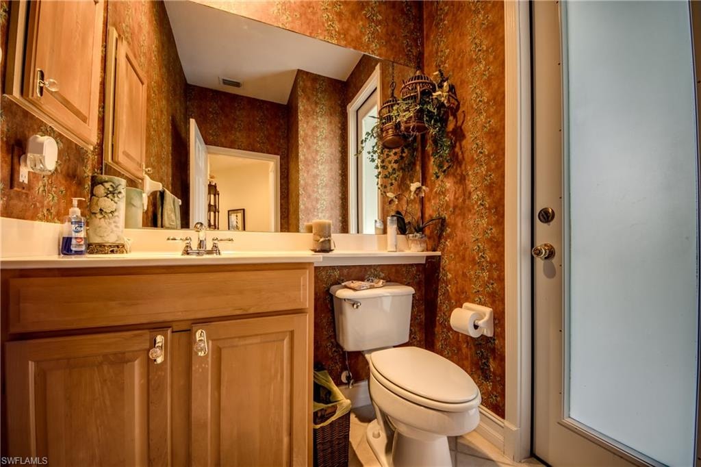 Half bathroom featuring vanity and wallpapered walls