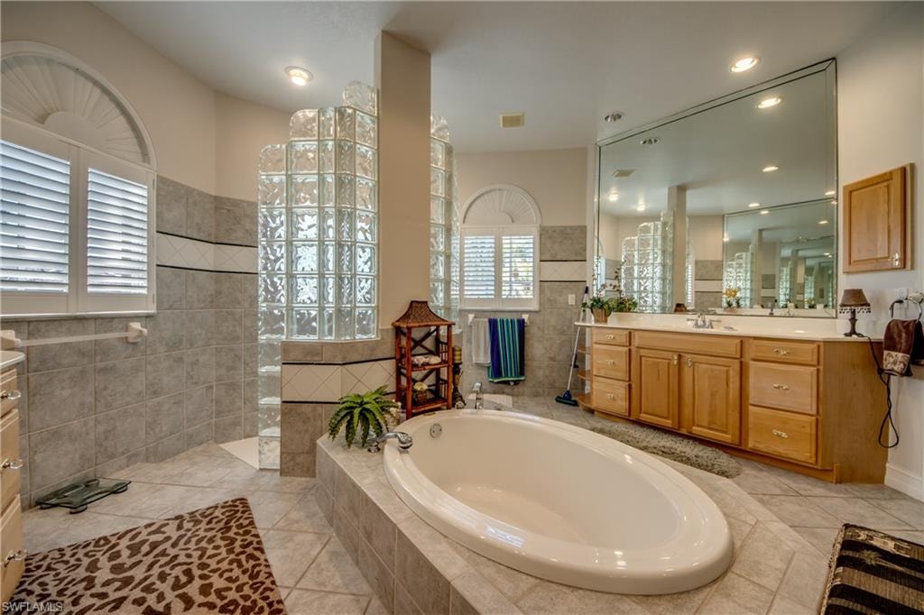 Bathroom with vanity, walk in shower, a garden tub, light tile patterned floors, and recessed lighting