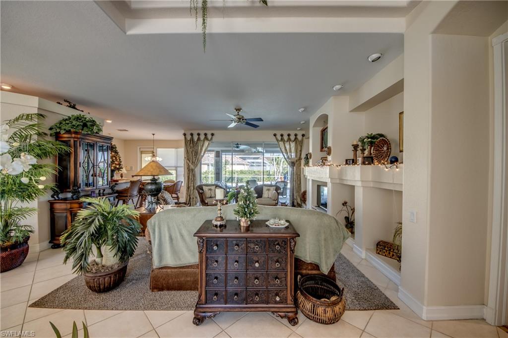 Tiled living room with a fireplace, ceiling fan, and recessed lighting