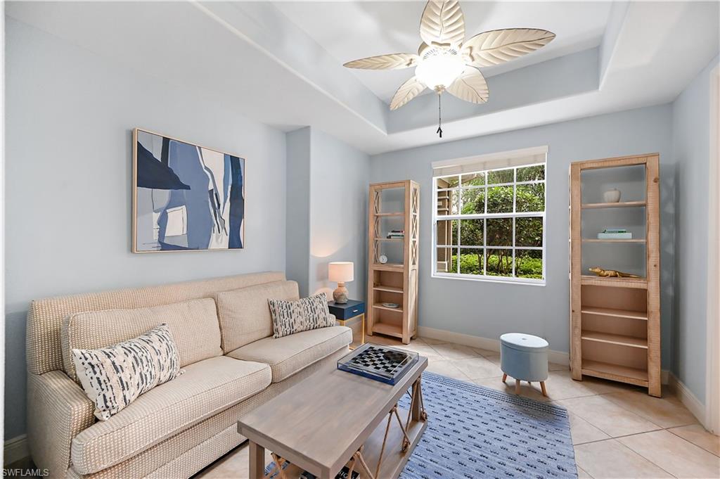 Living room featuring a ceiling fan, a raised ceiling, and tile patterned floors