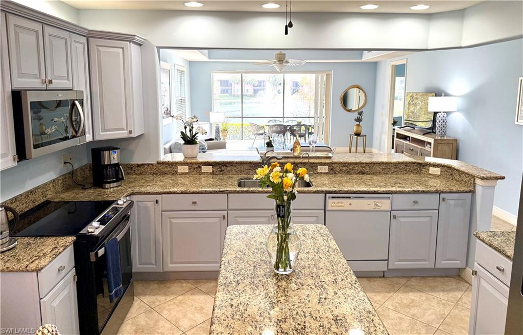 Kitchen featuring gray cabinetry, black range with electric stovetop, light stone counters, stainless steel microwave, and dishwasher