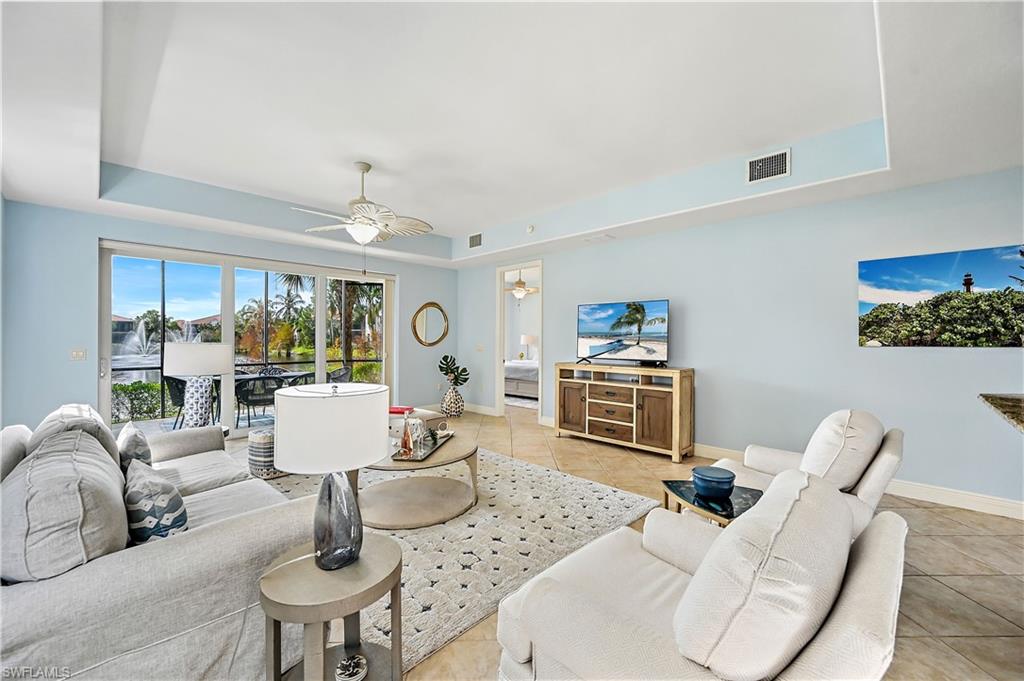 Tiled living room featuring a raised ceiling and a ceiling fan