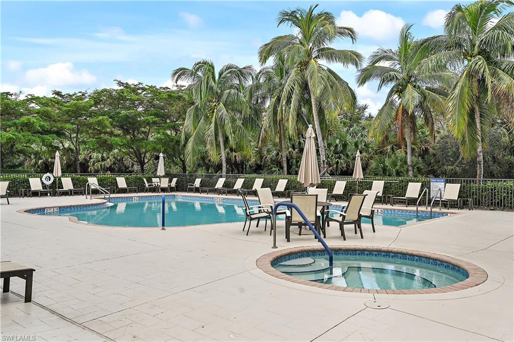 Community pool with a patio, a hot tub, and view of wooded area