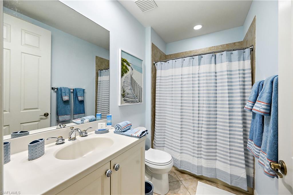 Full bathroom with curtained shower, vanity, and light tile patterned floors