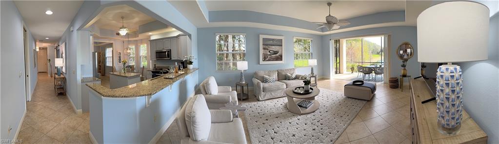 Living room featuring a ceiling fan, light tile patterned floors, and a tray ceiling