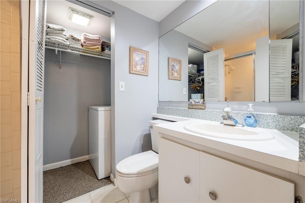 Full bathroom with vanity, washer / dryer, and light tile patterned flooring