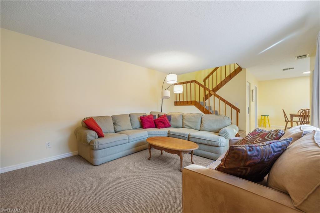 Carpeted living room with stairway and baseboards