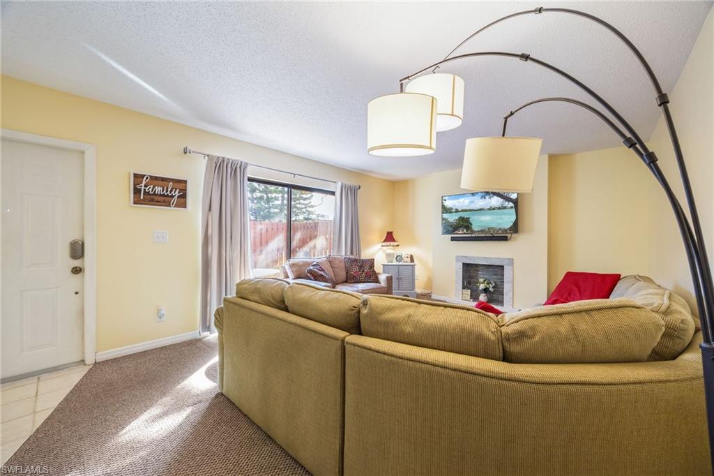 Living room featuring a fireplace, light tile patterned flooring, and light carpet